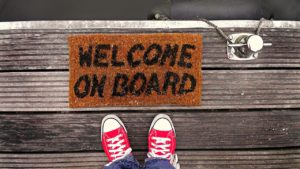 Rote Converse vor einem Fussabstreifer mit dem Text "Welcome on board"